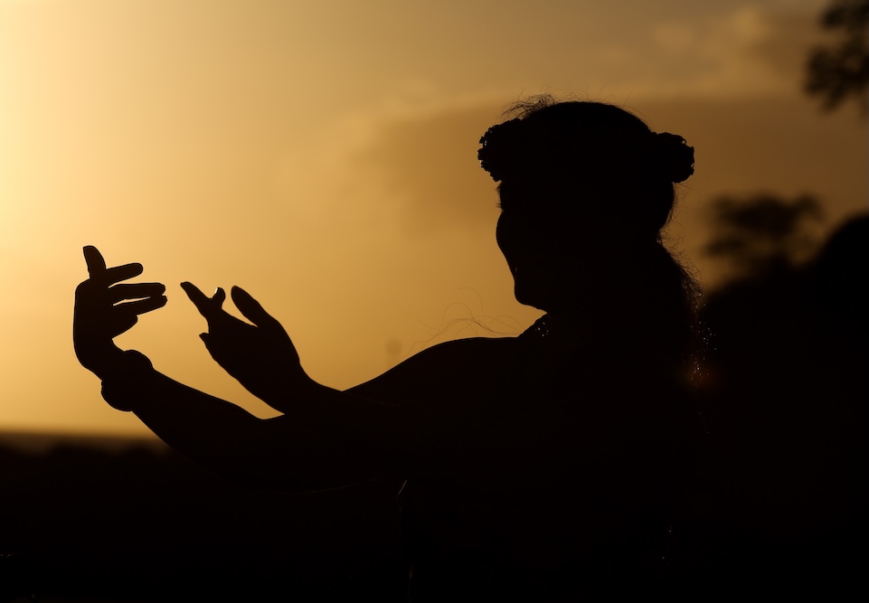 Silhouette of a woman dancing hula